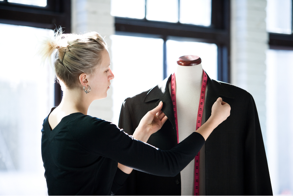 A woman measuring a suit on a mannequin, ensuring a perfect fit for the garment.